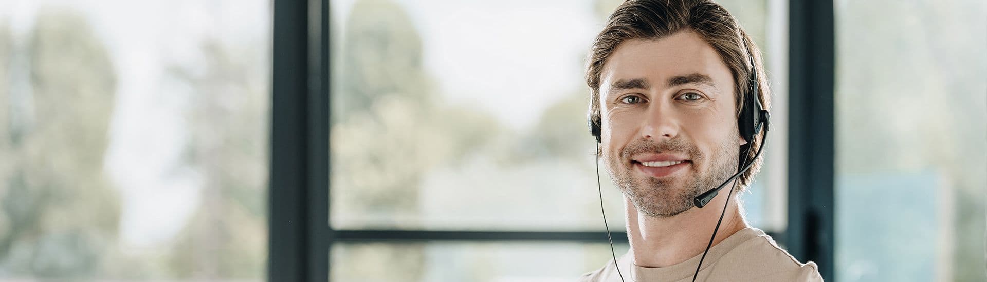 Junger Mann mit Headset lächelt freundlich und symbolisiert den Kundendienst.